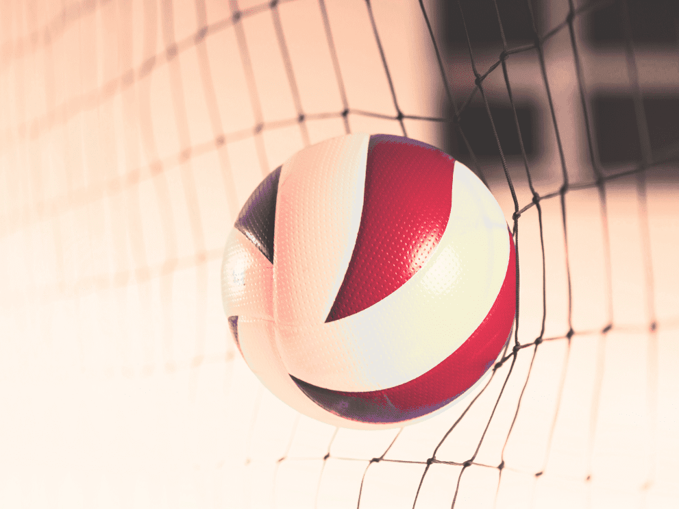 Nahaufnahme eines Volleyballs, der im Netz h&auml;ngt, mit rot-wei&szlig;er Farbgebung auf einem blassen Hintergrund.