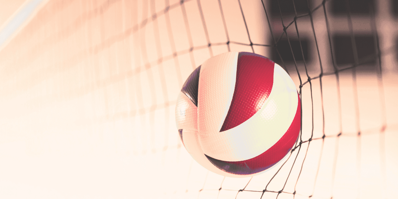 Nahaufnahme eines Volleyballs, der im Netz h&auml;ngt, mit rot-wei&szlig;er Farbgebung auf einem blassen Hintergrund.