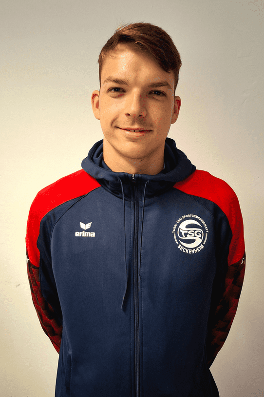 Porträt eines jungen Mannes in Sportjacke mit dem Logo der TSG Seckenheim vor neutralem Hintergrund.