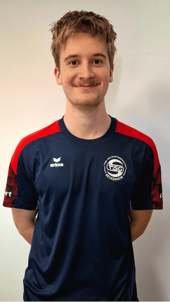 Junger Mann mit blondem Haar, tr&auml;gt ein dunkelblaues Sporttrikot mit rotem Design und Logo der TSG Seckenheim.