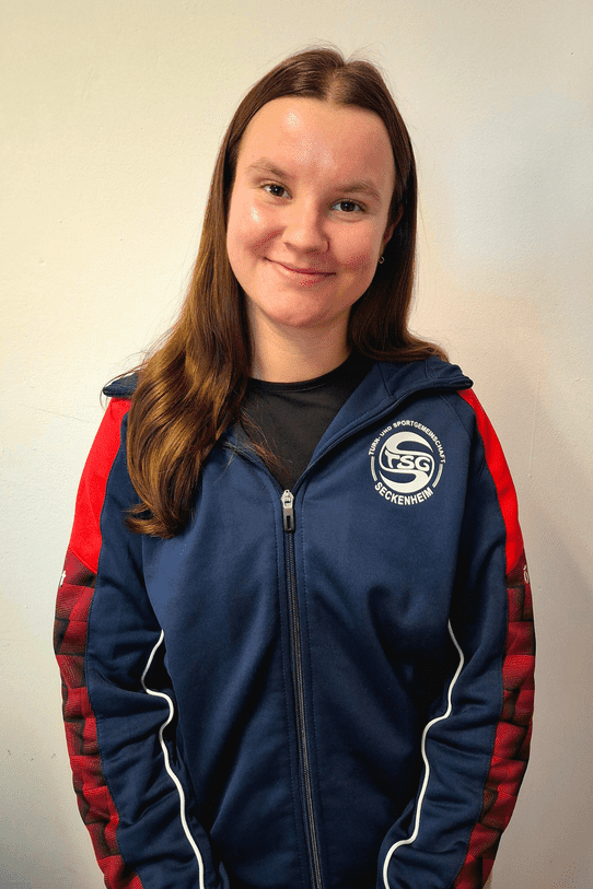 Junge Frau mit braunen Haaren trägt eine sportive Jacke der TSG Seckenheim vor einem neutralen Hintergrund.