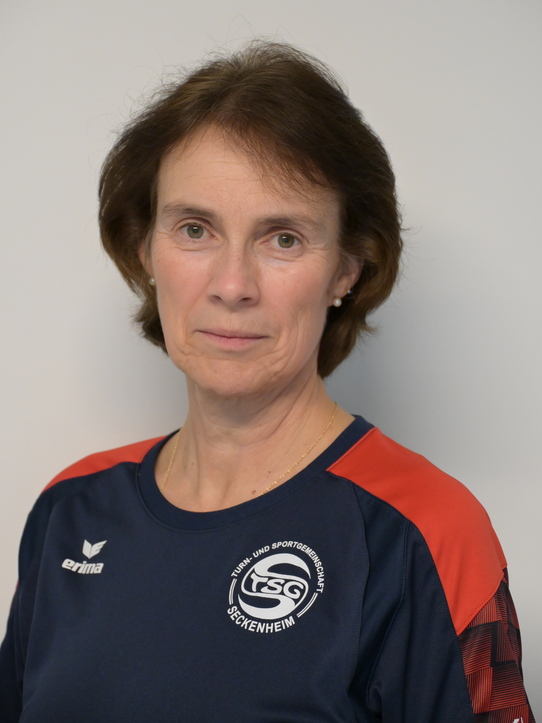 Portr&auml;t einer Frau mit kurzen braunen Haaren, die ein sportliches T-Shirt mit dem Logo der TSG Seckenheim tr&auml;gt.